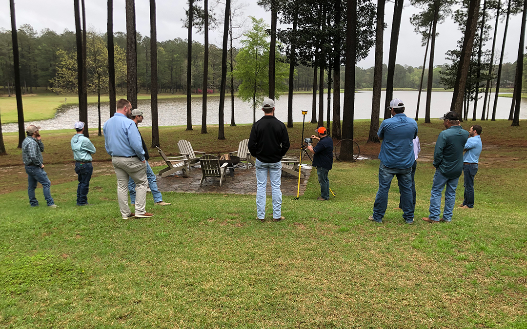 SITECH Louisiana team members watching a construction technology demonstration outdoors.